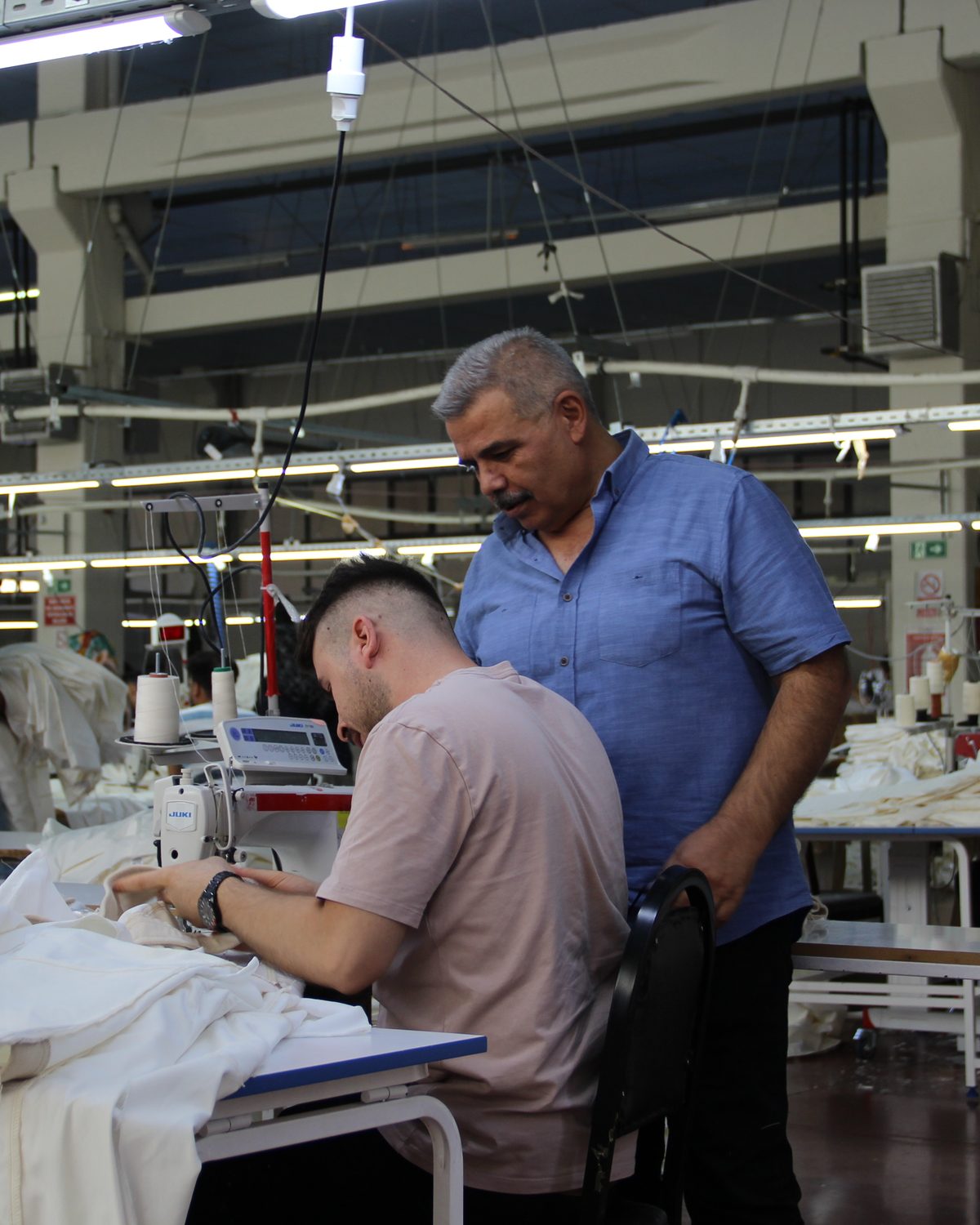 An experienced CRISTAL7 supervisor checking a sewing operator's work for quality